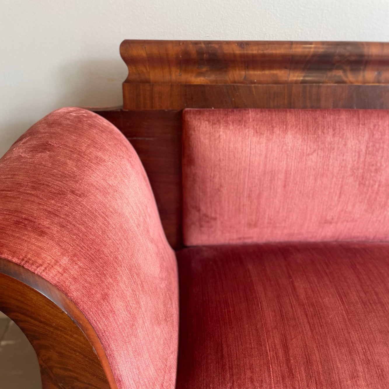 Vintage wooden sofa with red velvet upholstery on a plain background